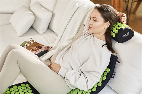 Moteris sėdi ant akupresūrinio kilimėlio